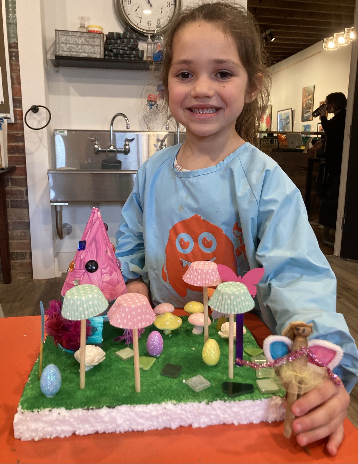 A young artist displaying a miniature fairy-garden sculpture