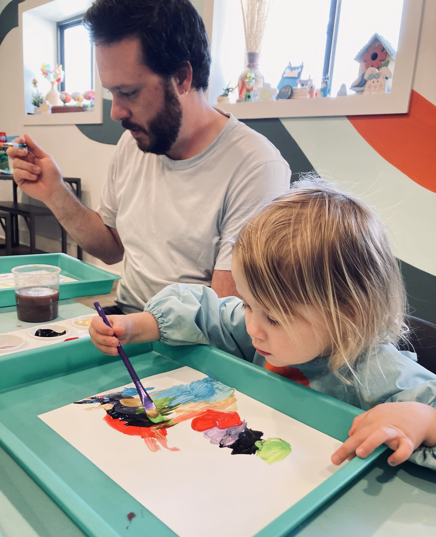 A child painting alongside an adult at the Art Bar