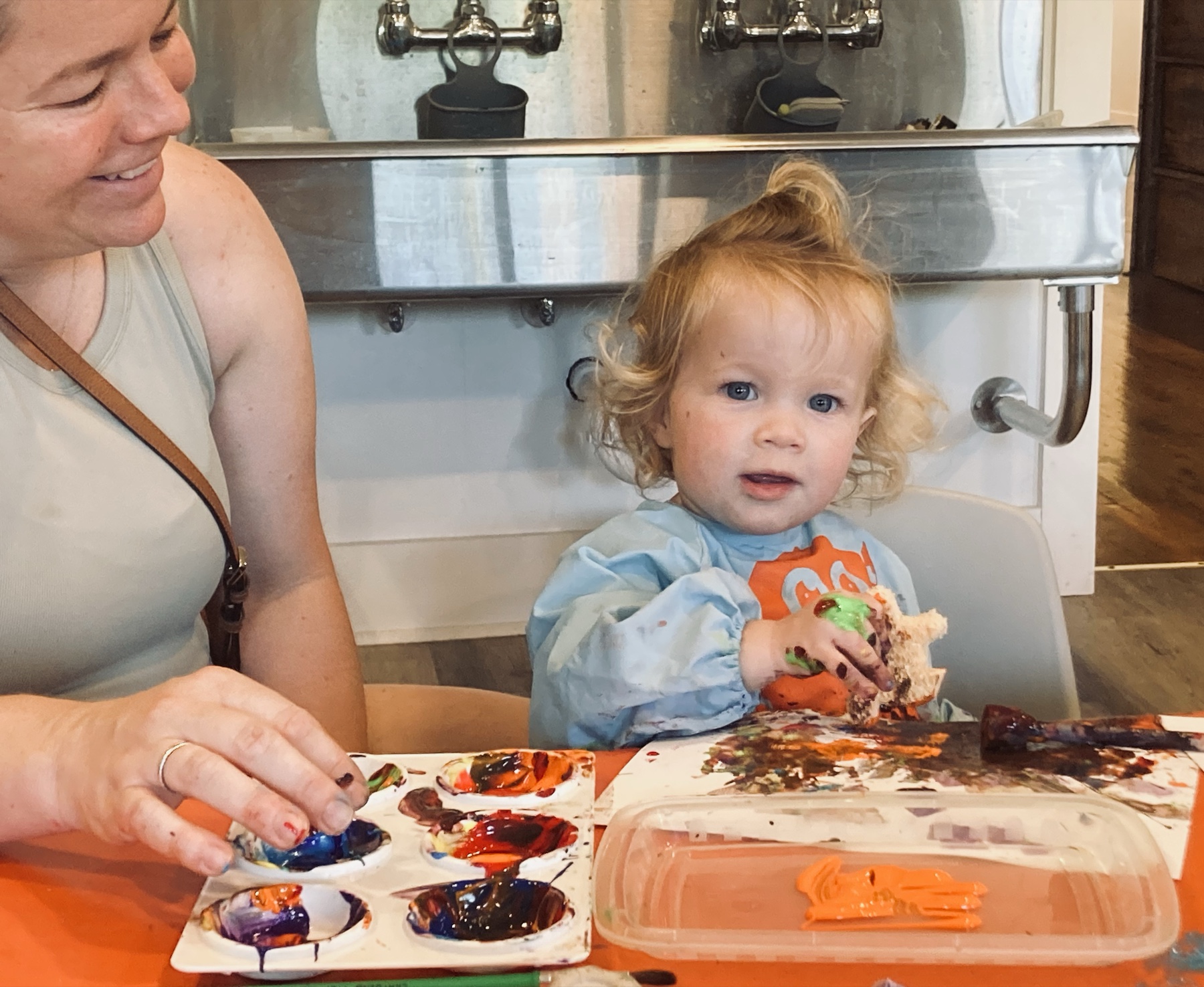 A toddler finger painting with an adult at the Art Bar