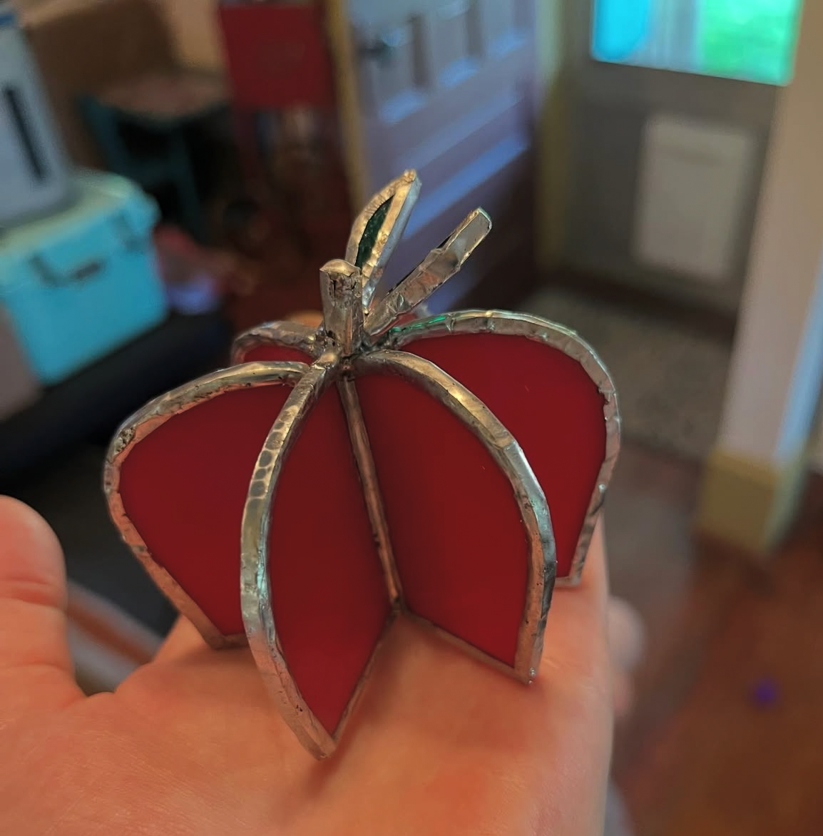 Red stained-glass pumpkin held in a hand
