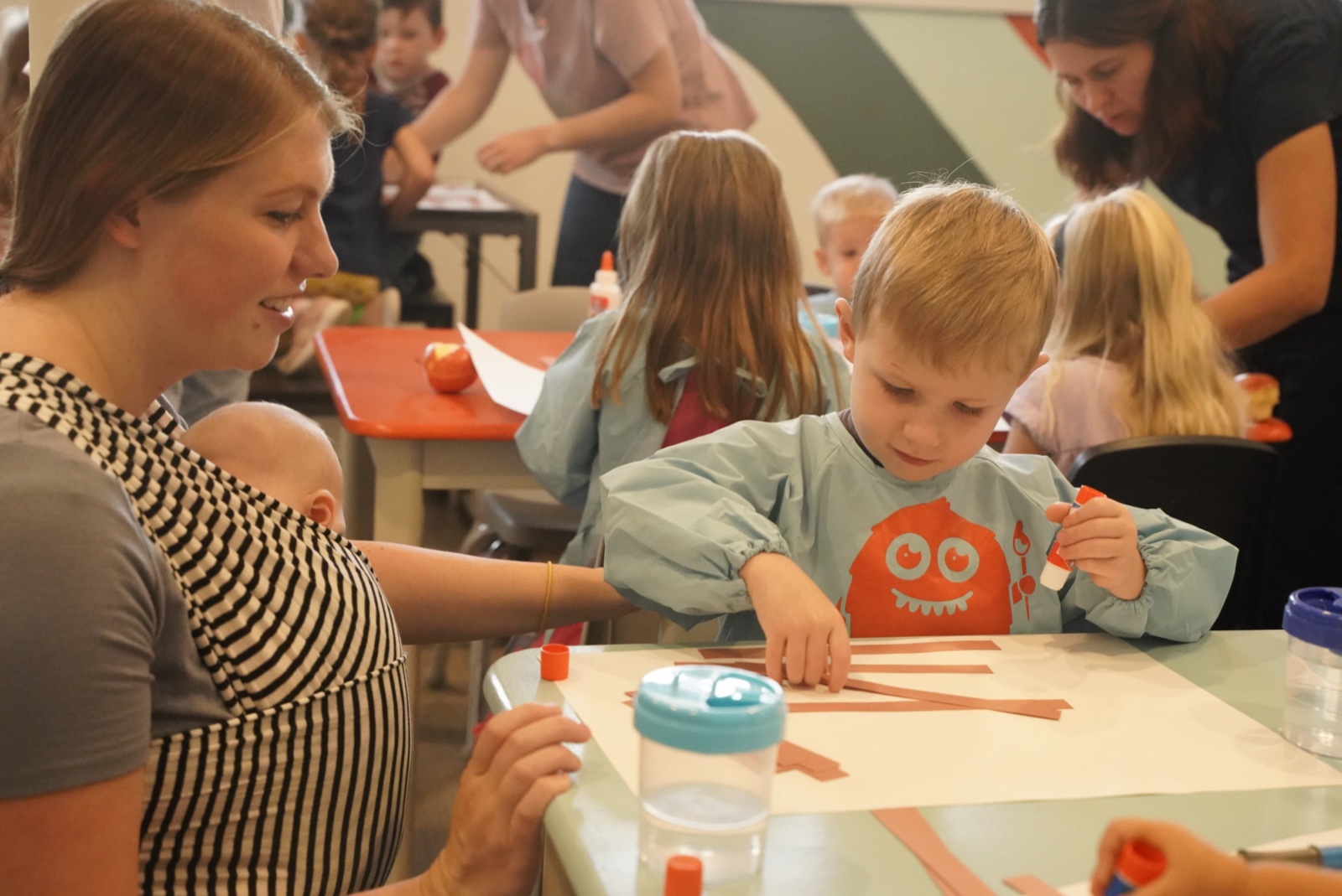 A child and adult making a colorful art project together at the studio table