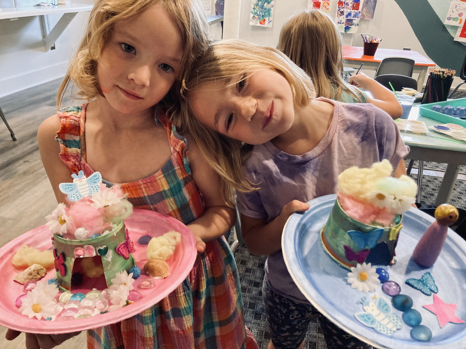 Two children holding their decorated sculpture projects