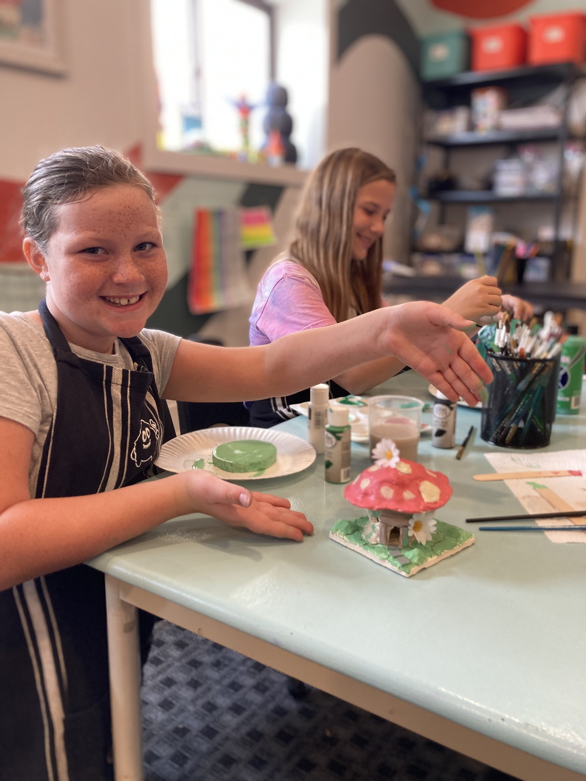Child painting a small mushroom sculpture at the studio