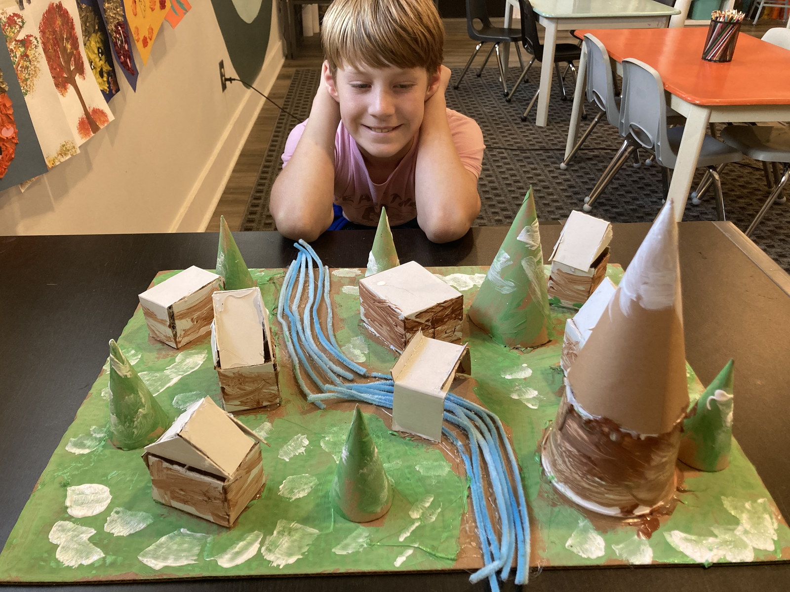 A young artist showing a colorful handmade landscape