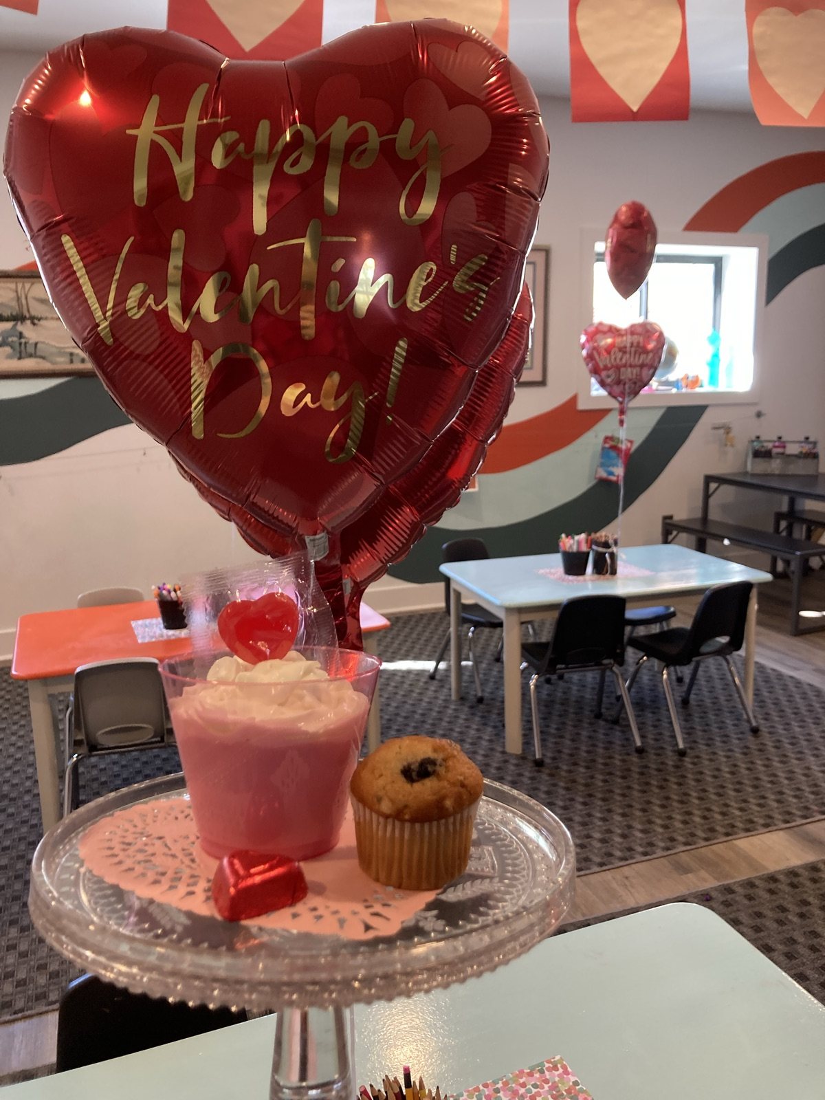 A Valentine’s Day party display with heart balloons, a pink drink, and a muffin inside the studio