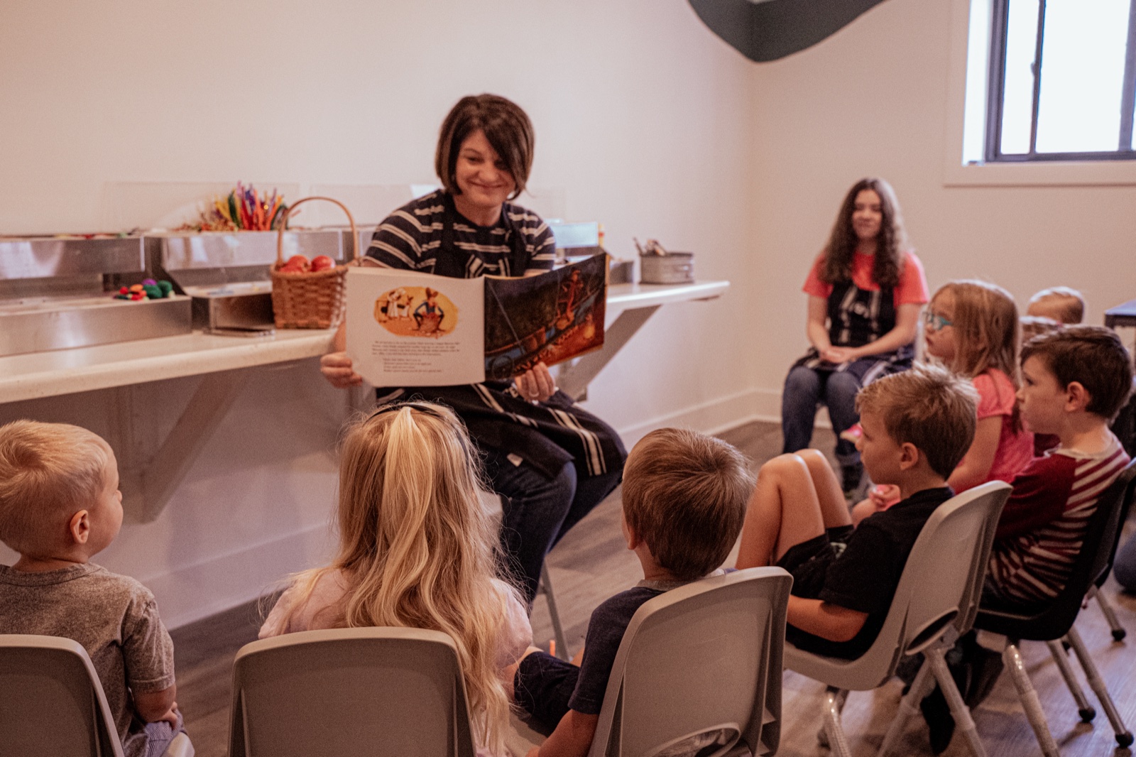 An instructor reading a picture book aloud to children during Story Hour