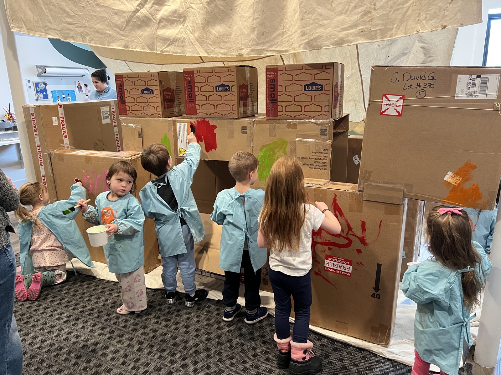 Children painting a large cardboard play structure together