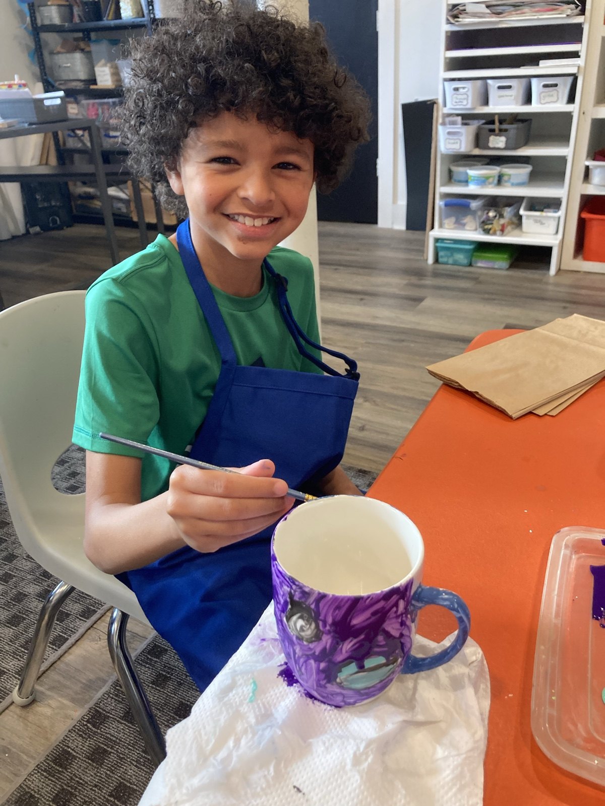 A young artist painting a purple ceramic mug at the studio